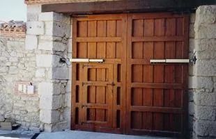 Puertas dobles de madera empotradas en muros de piedra.