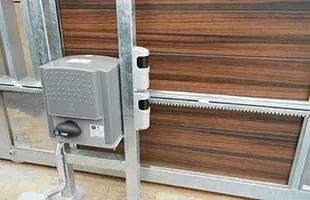 Puerta corredera automática con motor y sensores de seguridad. Paneles de puerta marrones.