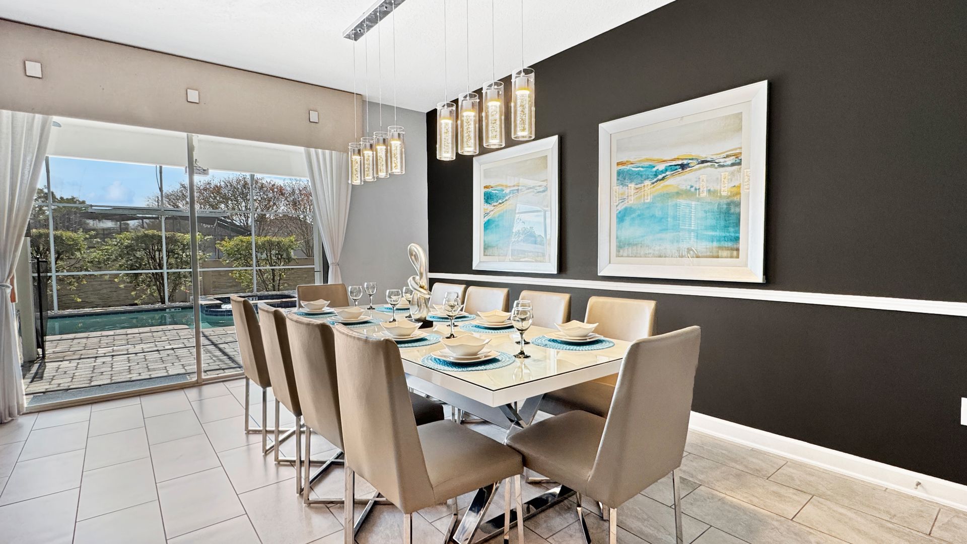 A dining room with a long table and chairs and a pool in the background.