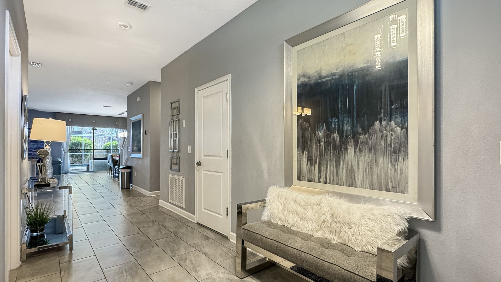 A hallway with a bench and a painting on the wall.
