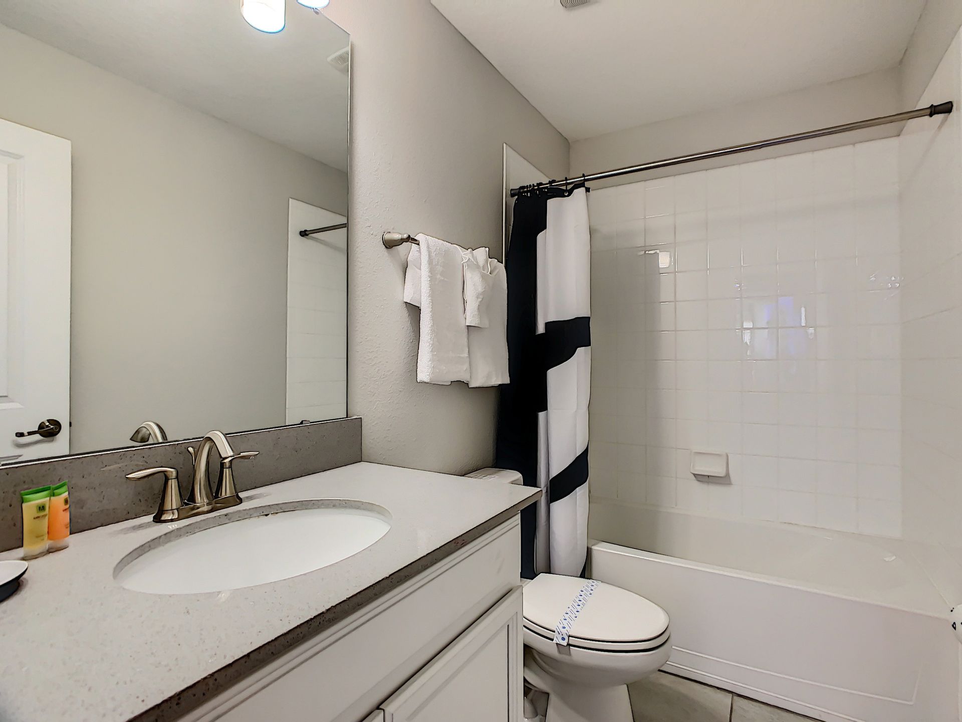 A bathroom with a sink , toilet , bathtub and mirror.