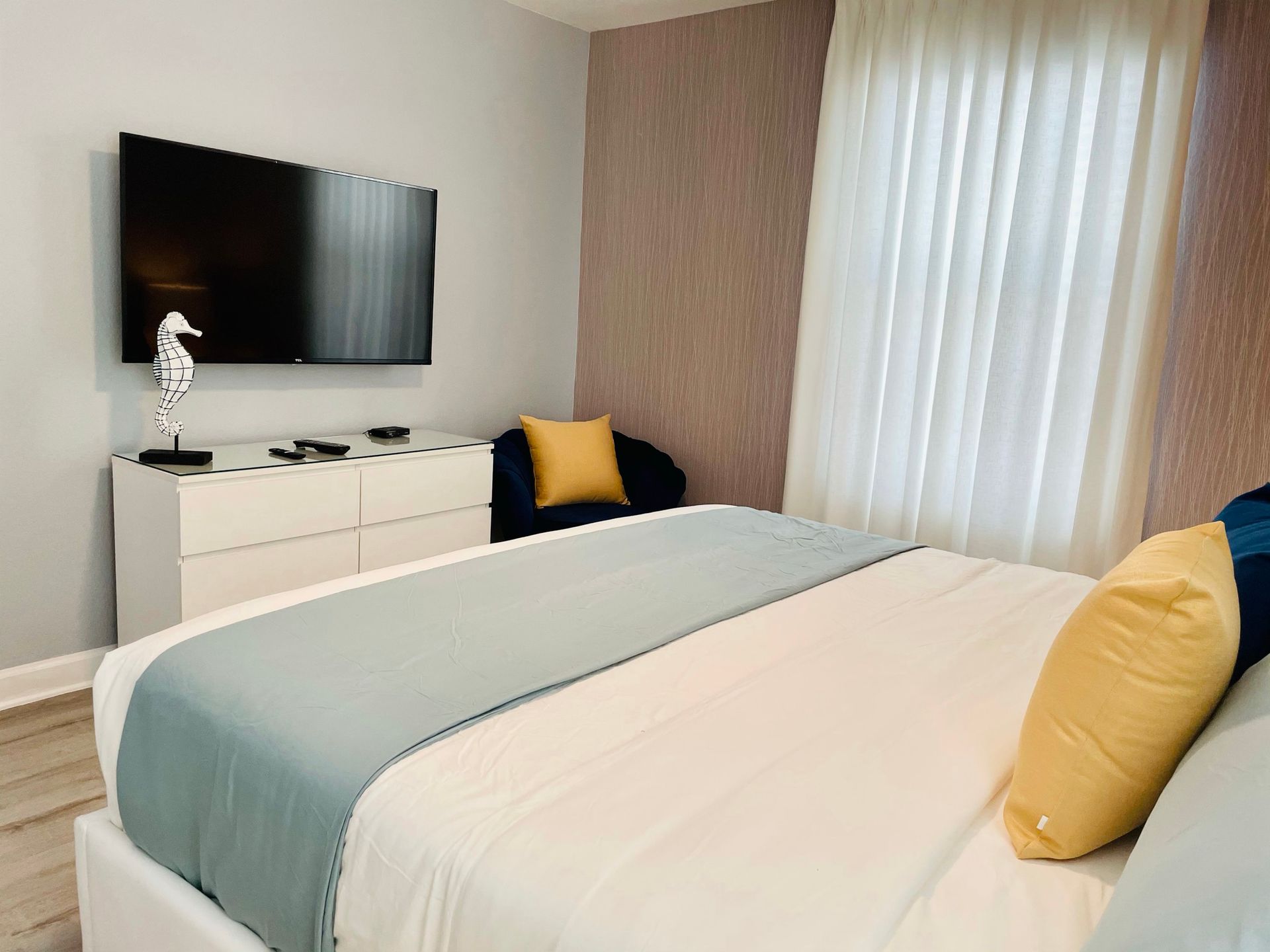 A bedroom with a bed , dresser , television and chair.