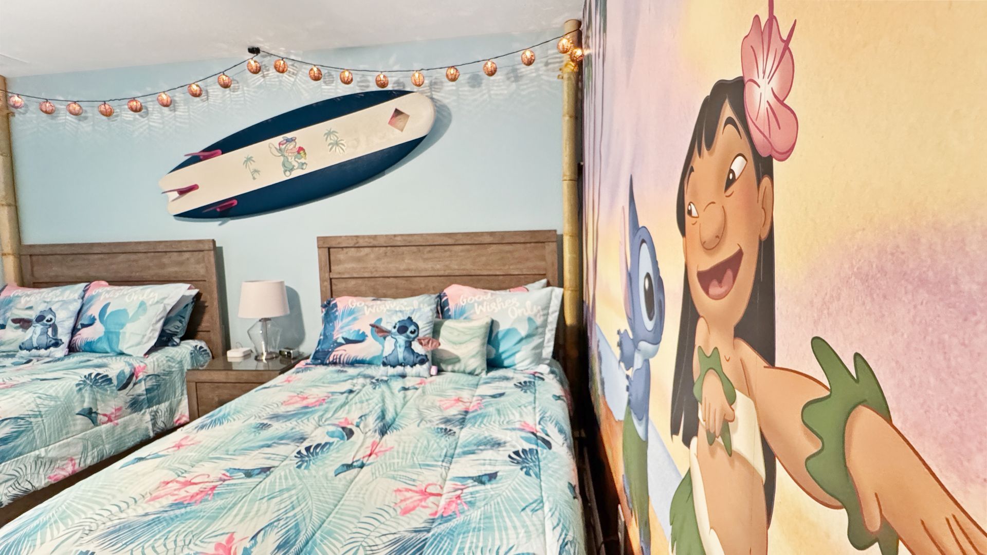 A bedroom with two beds and a painting of a surfboard on the wall.