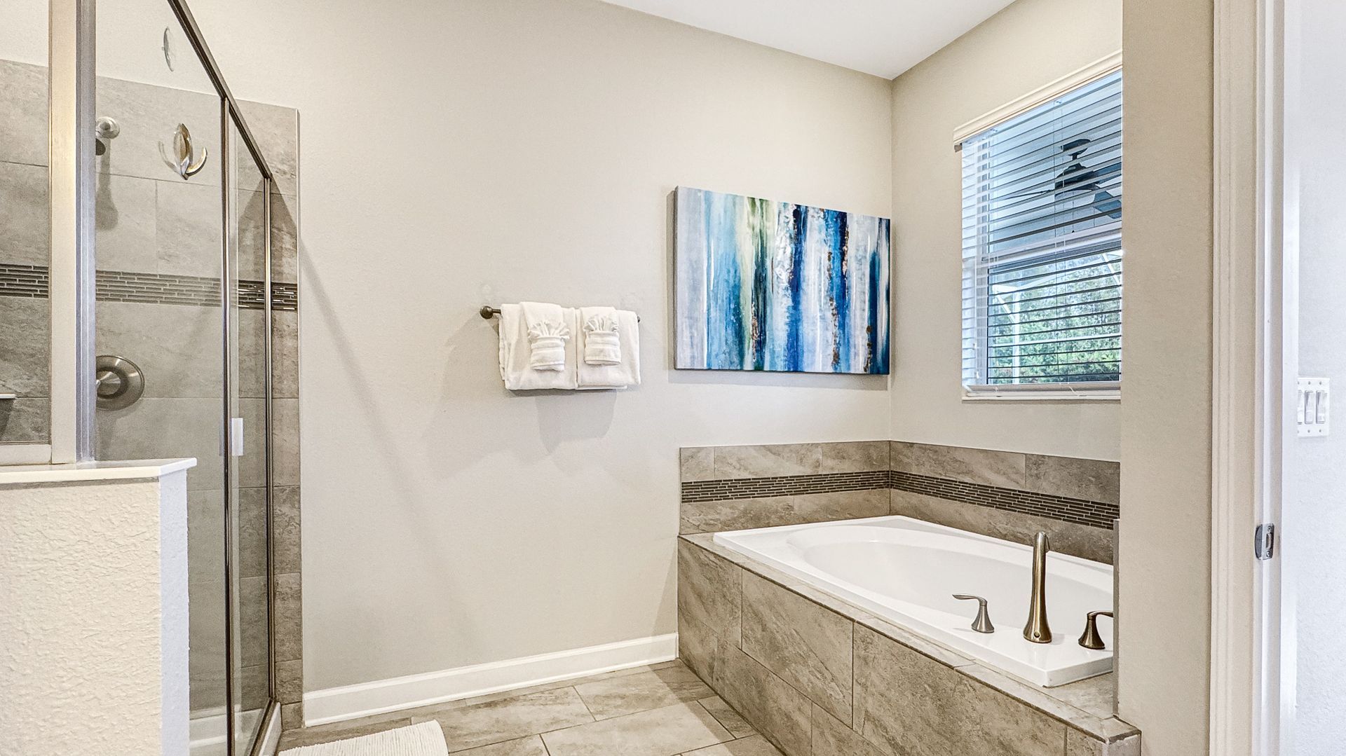 A bathroom with a tub , shower , and window.