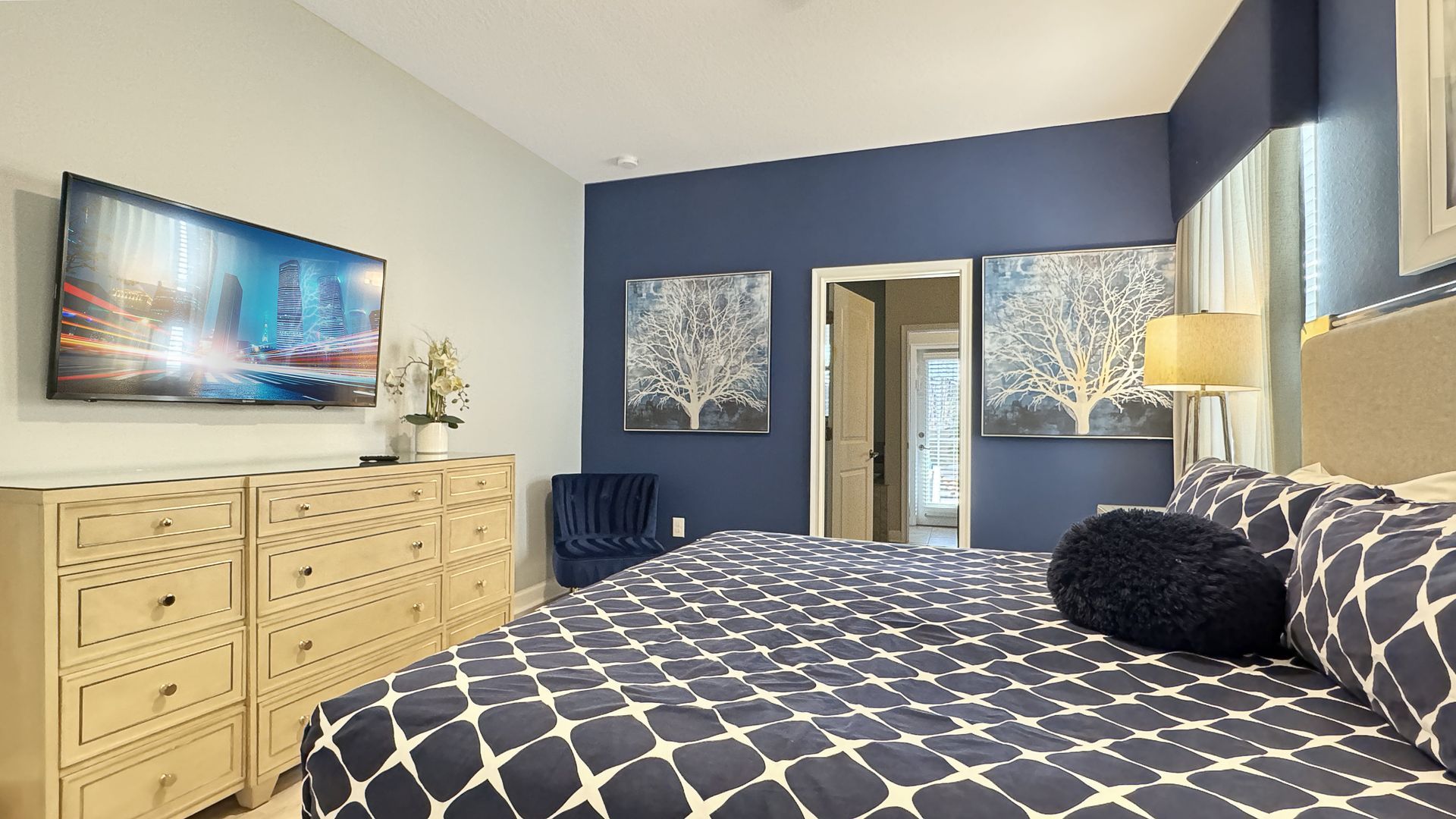 A bedroom with a bed , dresser , television and blue walls.