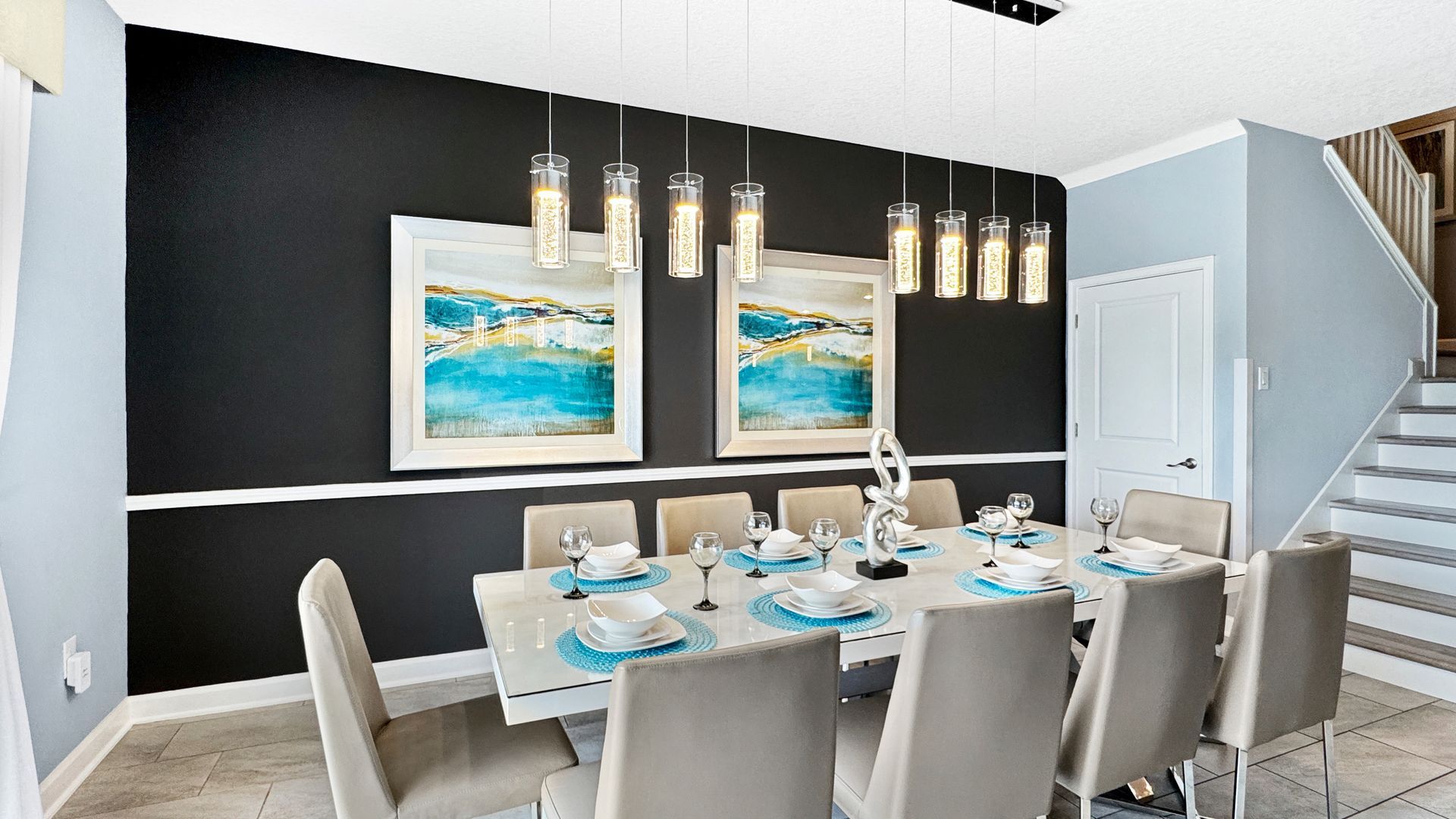 A dining room with a long table and chairs and stairs.