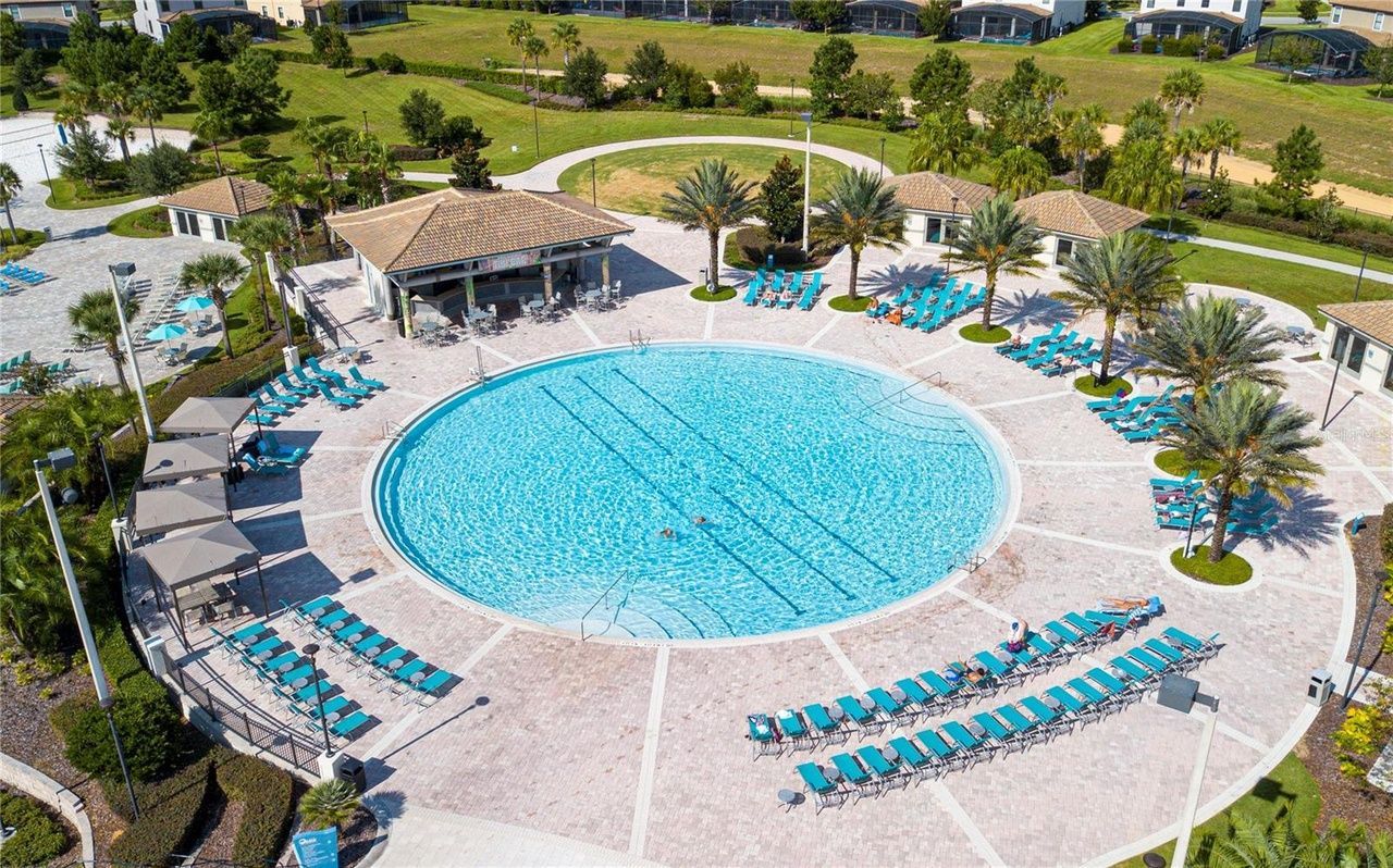 An aerial view of a large swimming pool surrounded by chairs and palm trees.