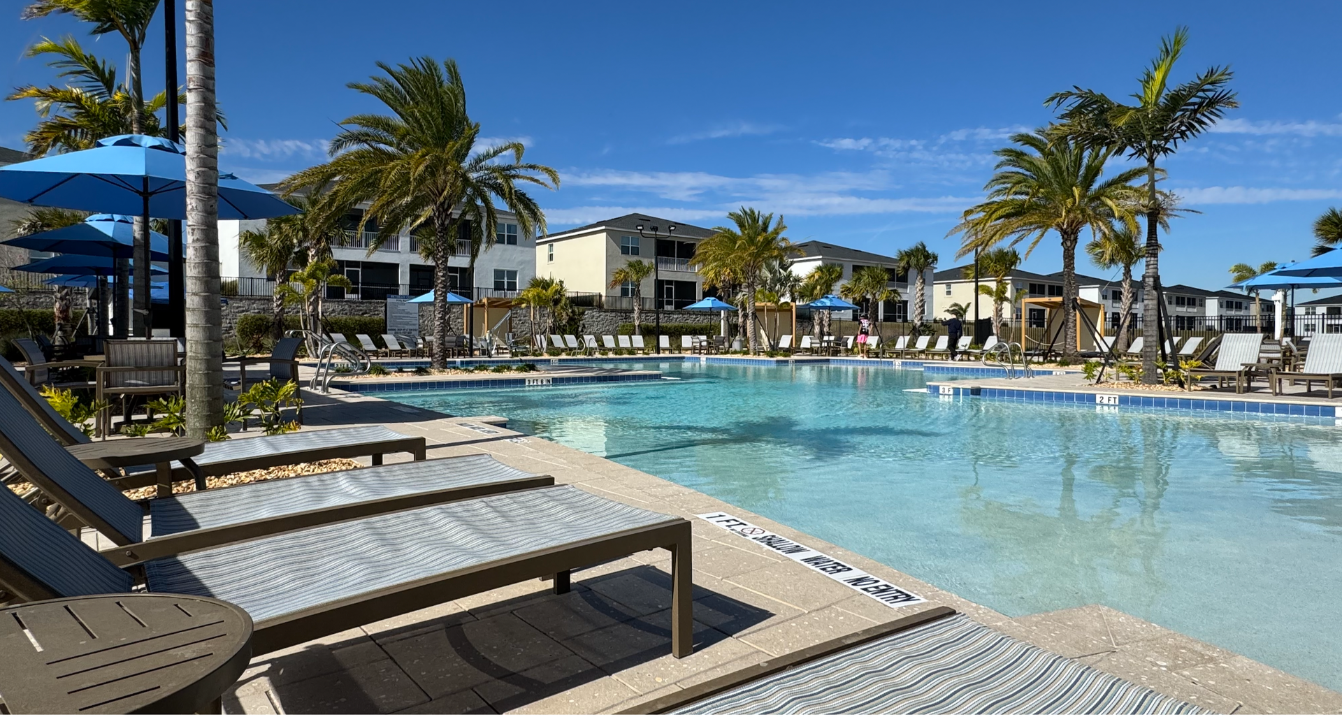 A large swimming pool surrounded by palm trees and chairs