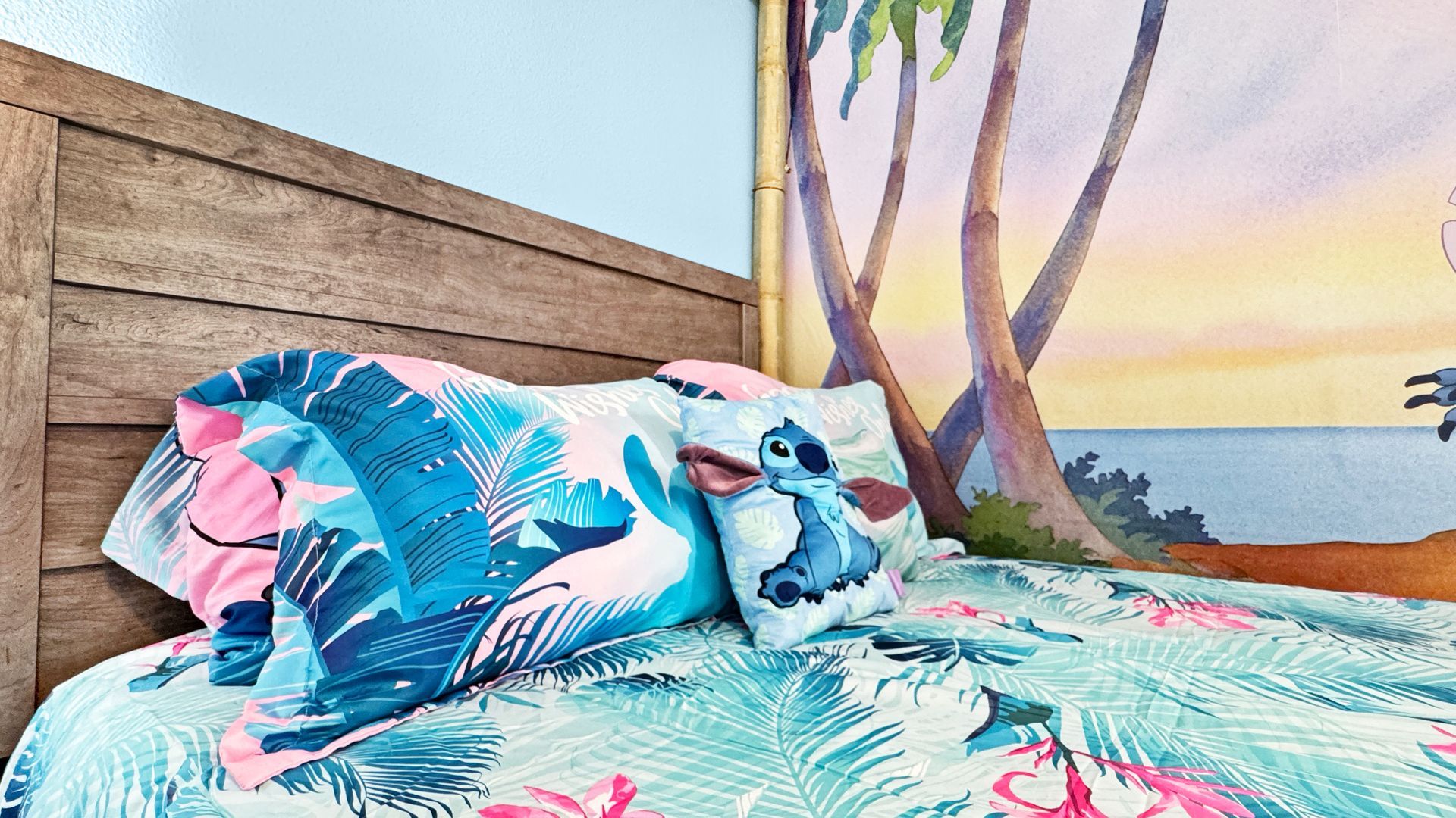 A bed with a lilo and stitch comforter and pillows in a bedroom.