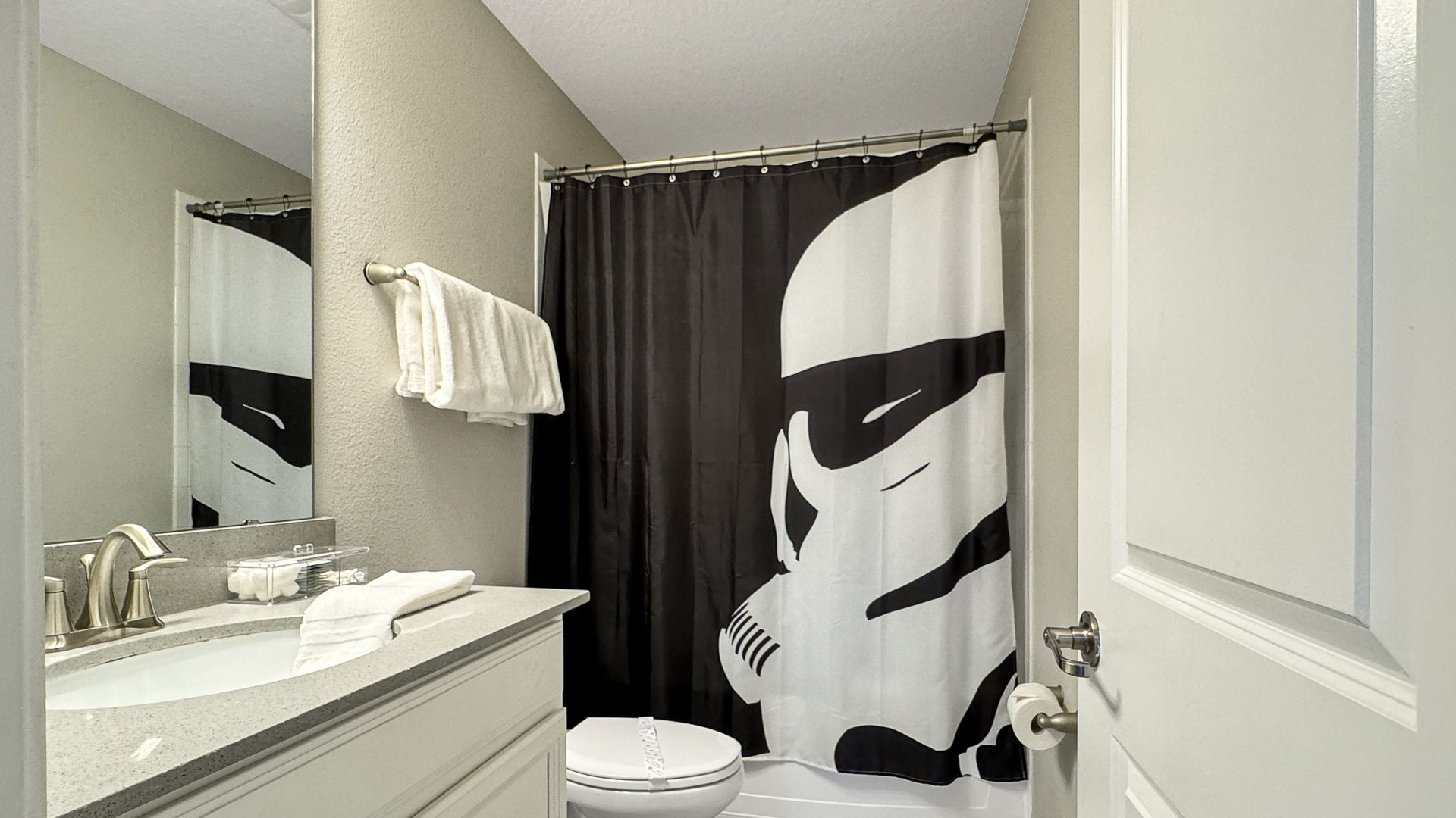 A bathroom with a storm trooper shower curtain and a toilet.