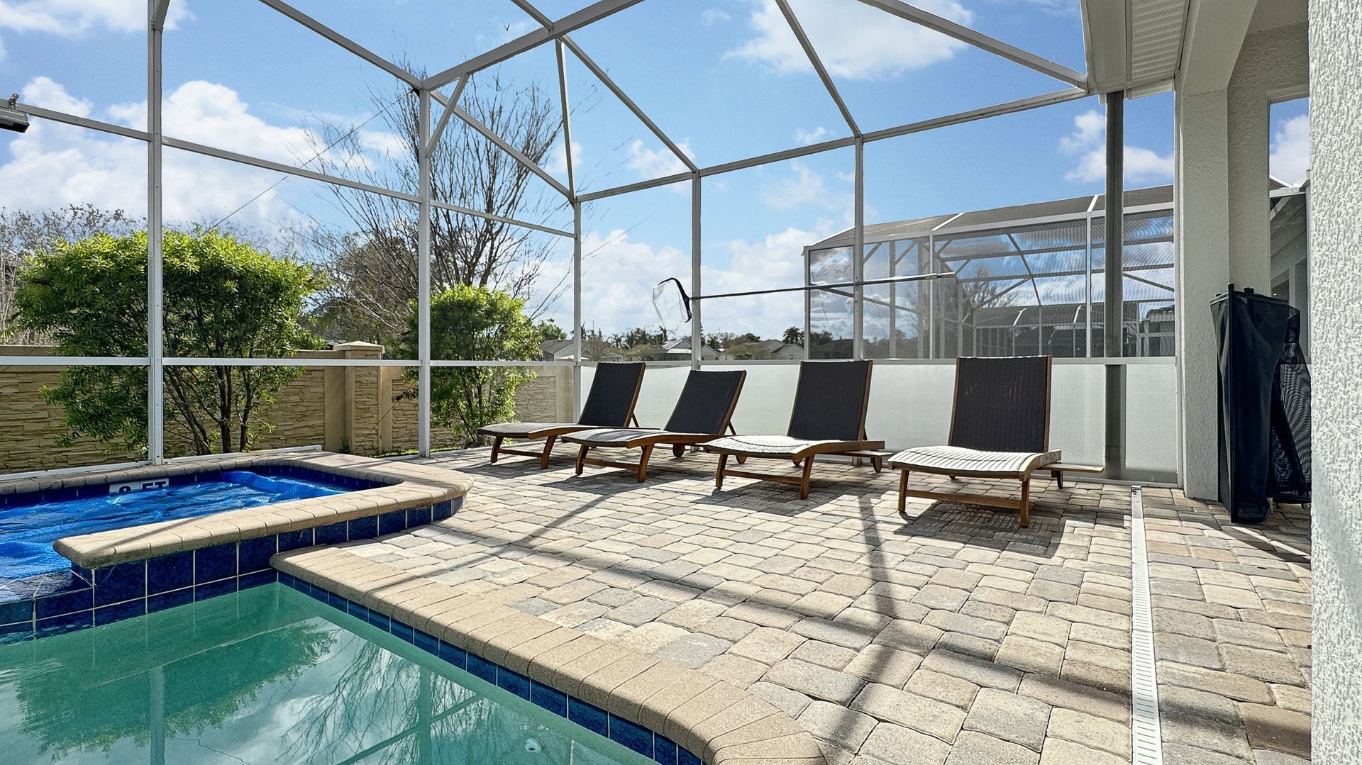 A swimming pool is surrounded by chairs and a screened in area.