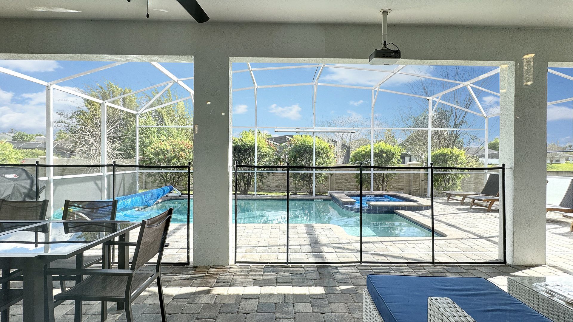 A patio with a table and chairs and a pool in the background.