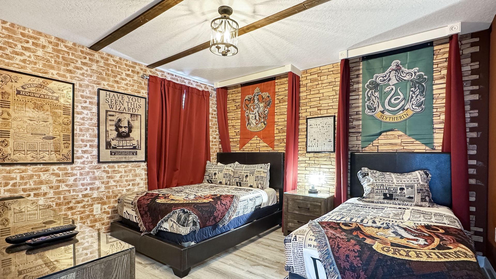 A bedroom with two beds and a slytherin tapestry on the wall.