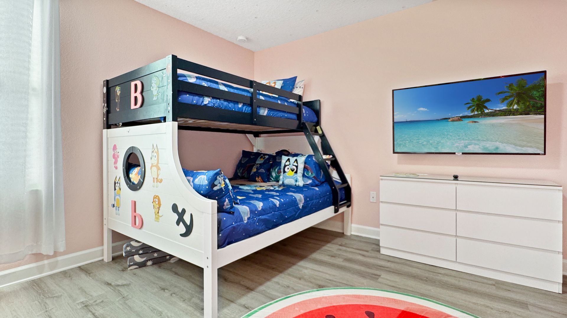 A bedroom with a bunk bed , dresser , and television.