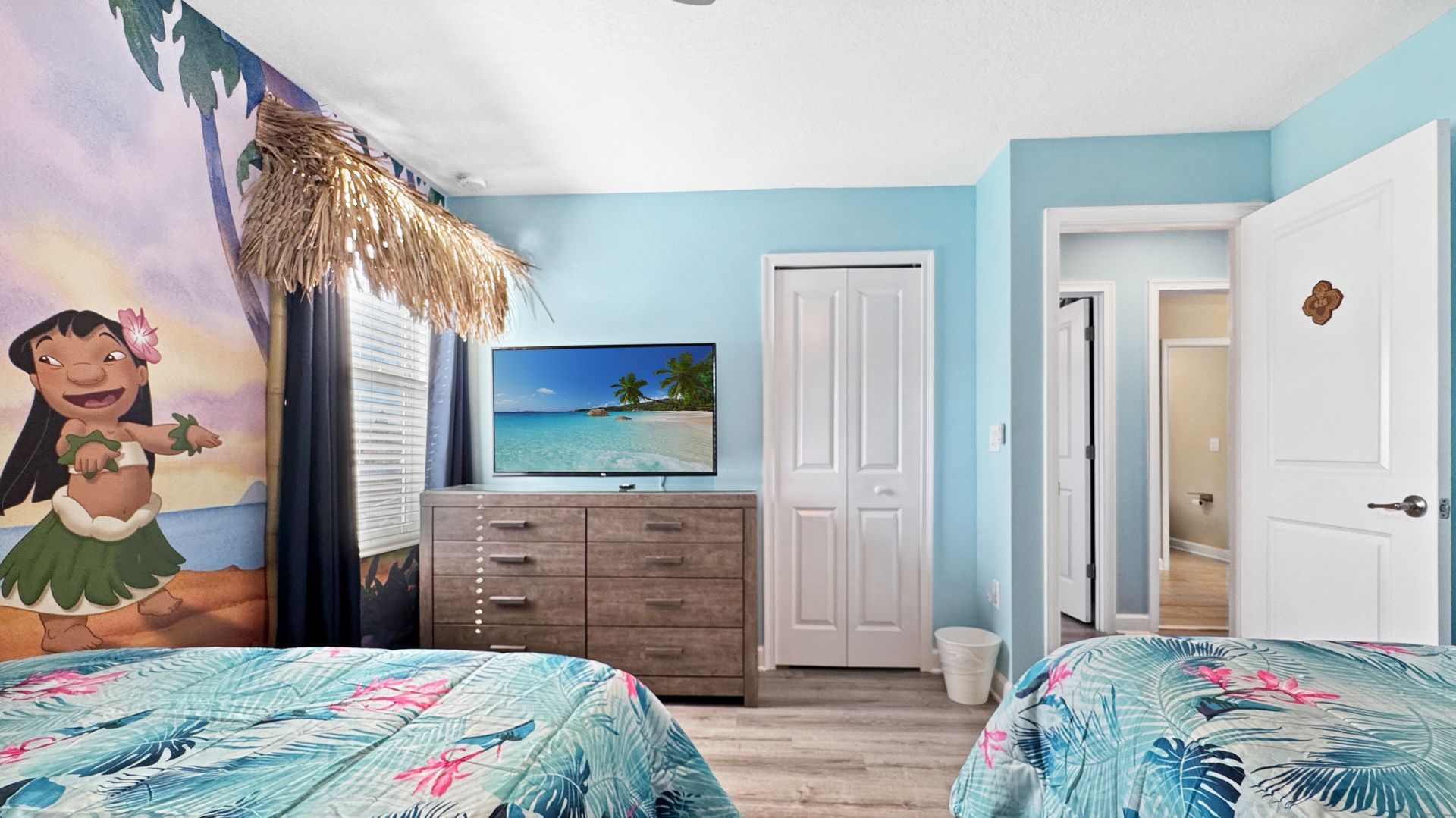 A bedroom with two beds , a dresser , and a television.