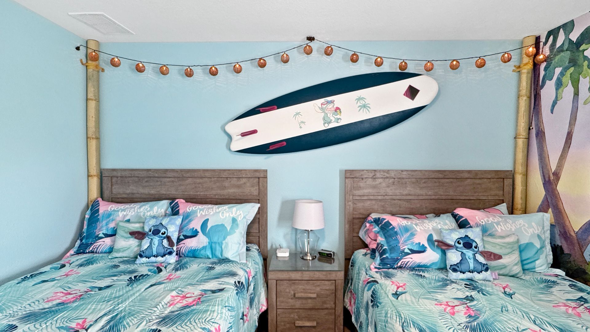 A lilo stitch bedroom with two beds and a surfboard on the wall.