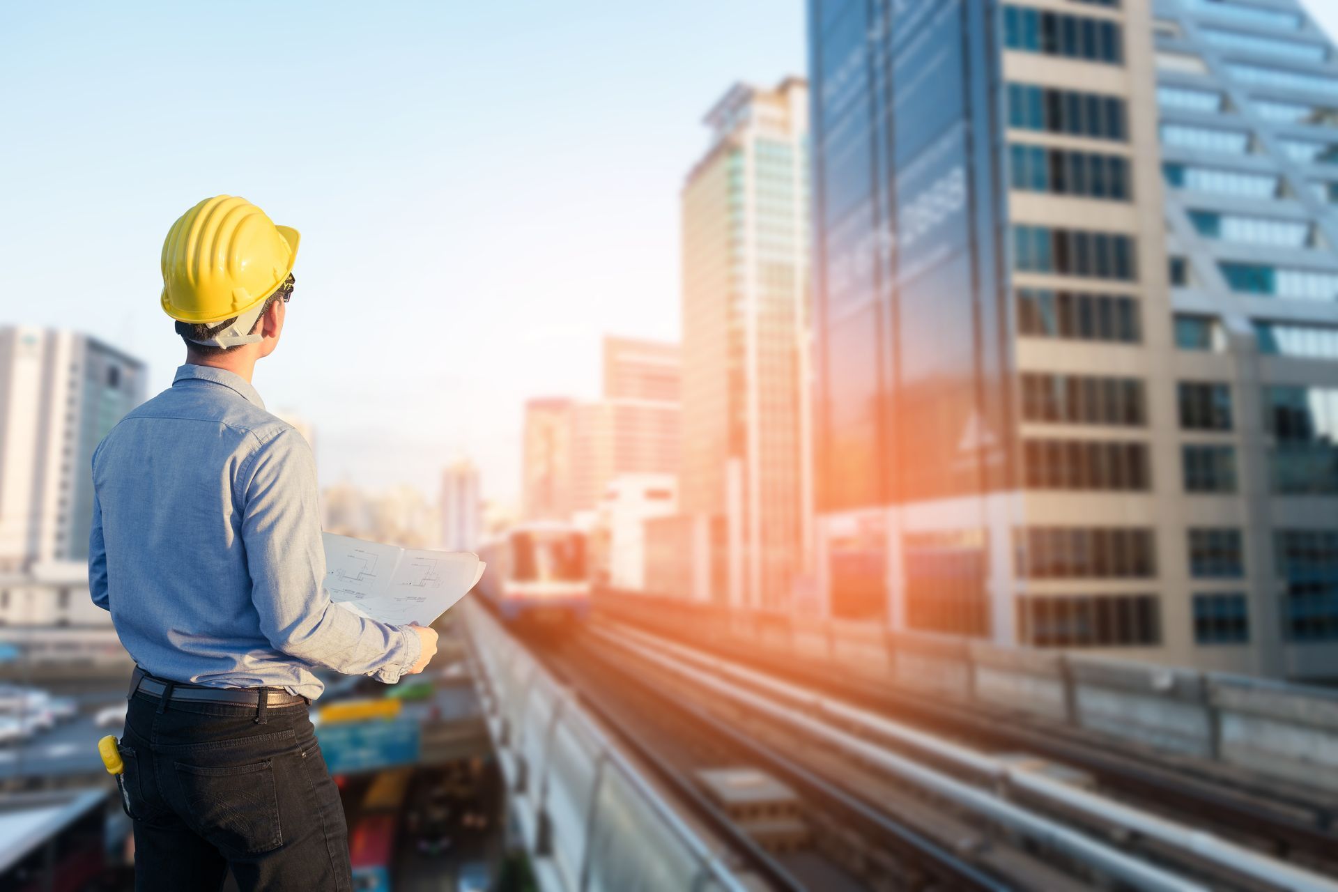 Un hombre que lleva un casco y sostiene un portapapeles mira una ciudad.