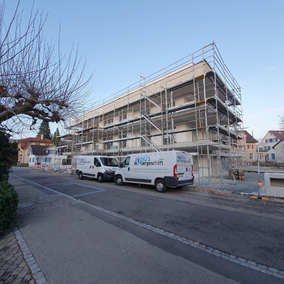 Fahrzeuge der Manu's Malergeschäft AG vor einem Gerüst