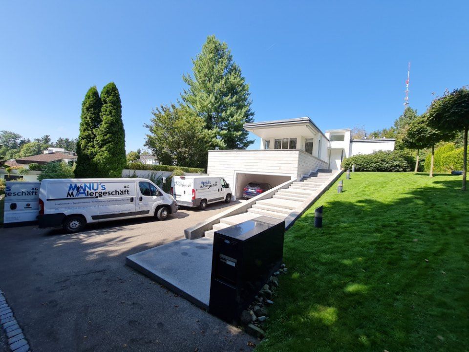 Fahrzeuge der Manu's Malergeschäft AG vor einem Haus