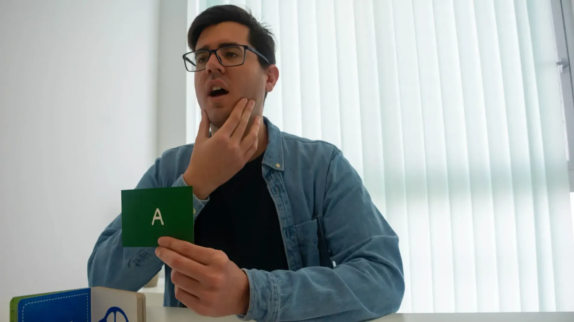 Hombre sosteniendo una tarjeta verde con la letra