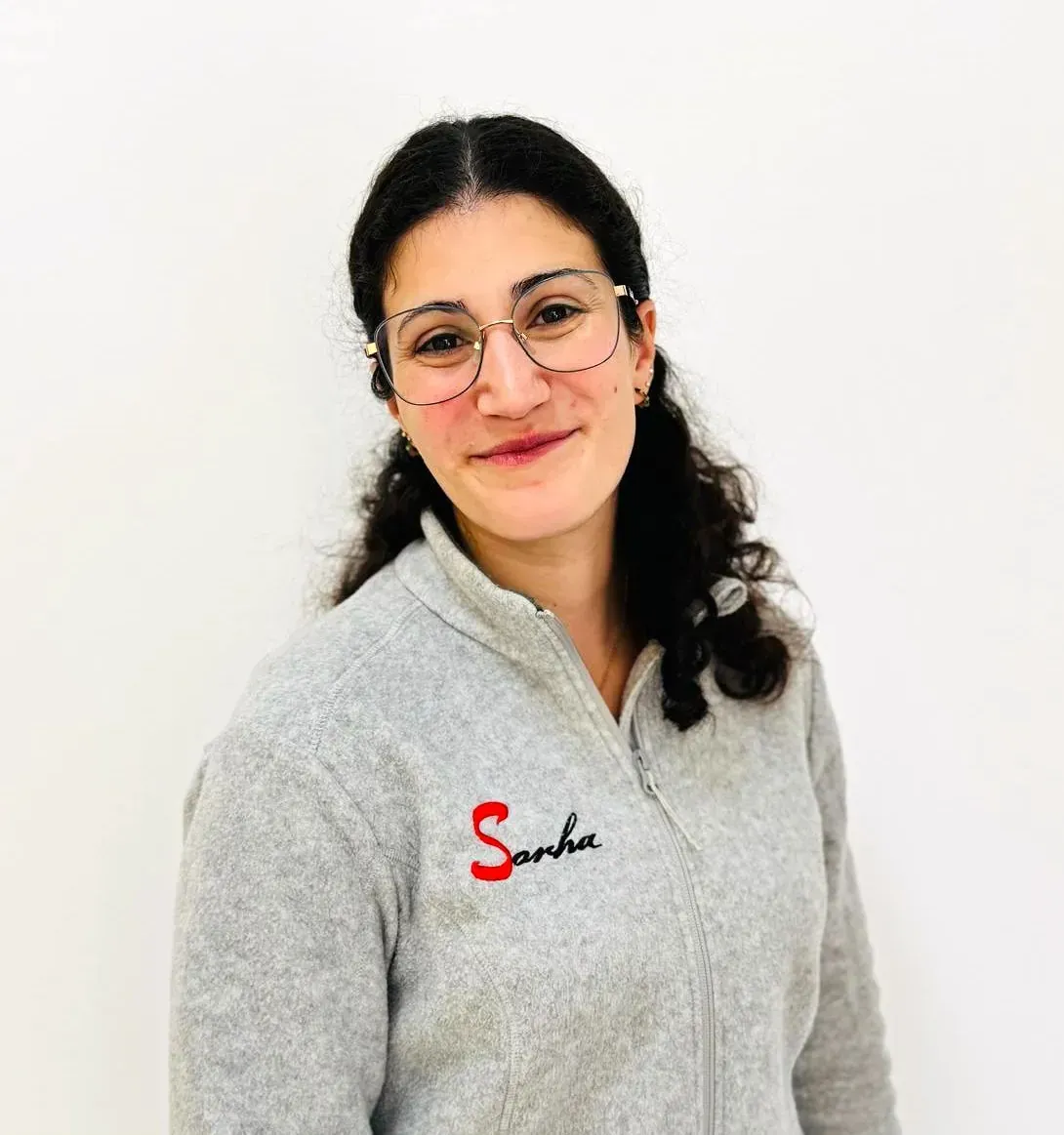 Una mujer con gafas y una chaqueta gris con la palabra 