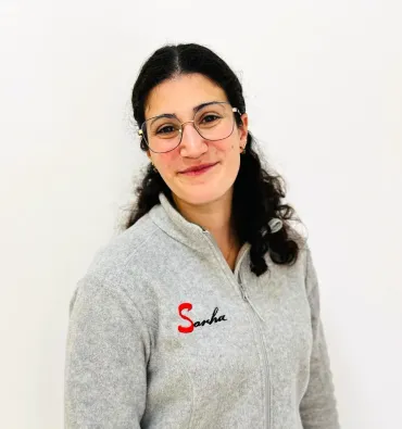 Una mujer con gafas y una chaqueta gris con la palabra 