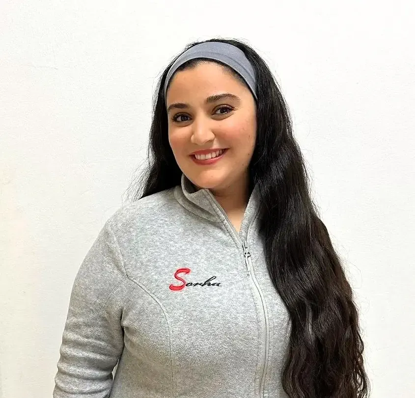 Mujer sonriente, con una diadema gris y una chaqueta con el logo 
