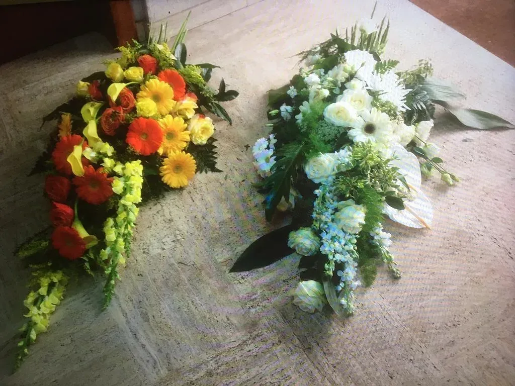 Deux compositions florales de deuil, une rouge et jaune et l'autre verte et blanche