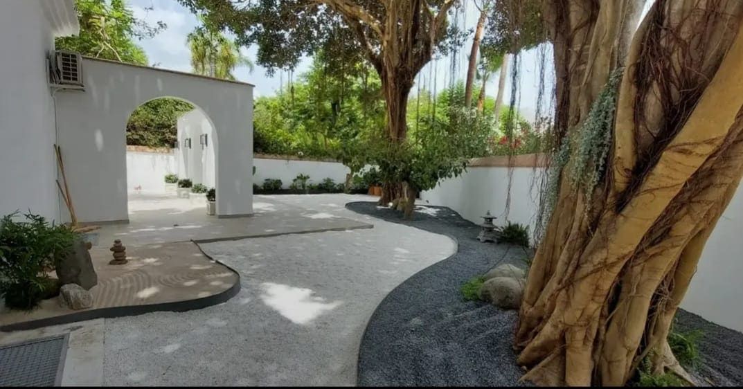 Un banco blanco en un parque rodeado de árboles y flores.