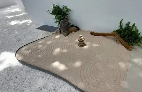 Un pequeño jardín de arena con una pila de rocas en el medio.