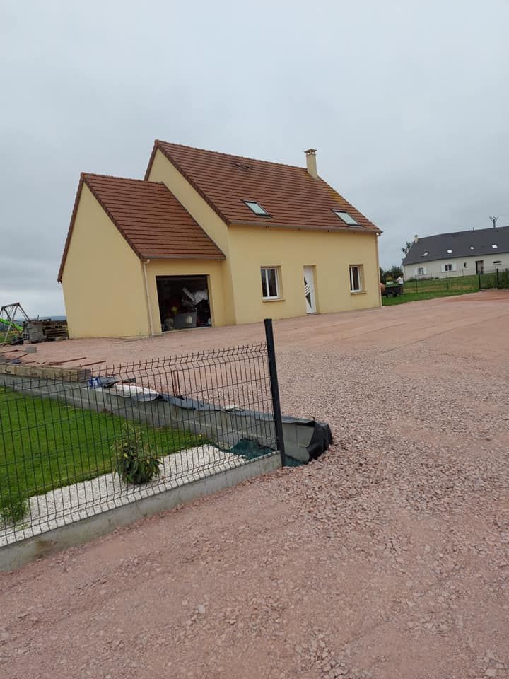 Maison jaune au toit de tuiles rouges, garage et allée de gravier.