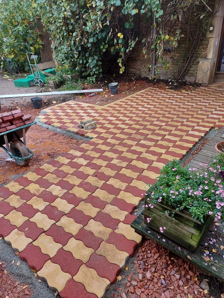 Aménagement d'une terrasse en briques avec des pavés autobloquants rouges et jaunes en extérieur.