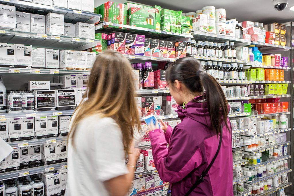 Deux personnes parcourent les rayons de cosmétiques dans une allée bien éclairée