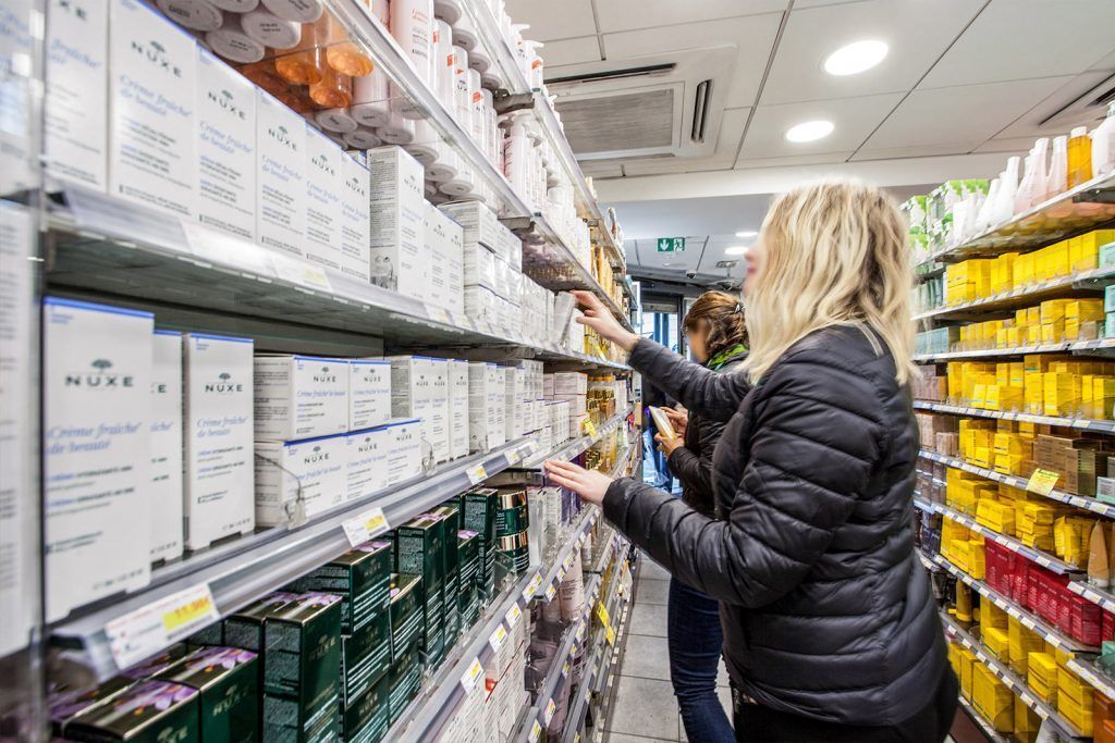 Un client se sert parmi les produits exposés sur les étagères d'un rayon lumineux d'un supermarché.