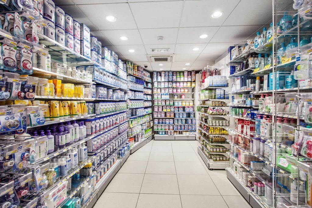 Une allée lumineuse de pharmacie bordée d'étagères remplies de produits d'hygiène, de médicaments et de produits ménagers.