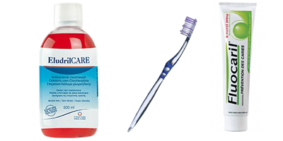 Produits de soins dentaires : bain de bouche EludrilCARE, brosse à dents et dentifrice Fluocaril sur fond blanc