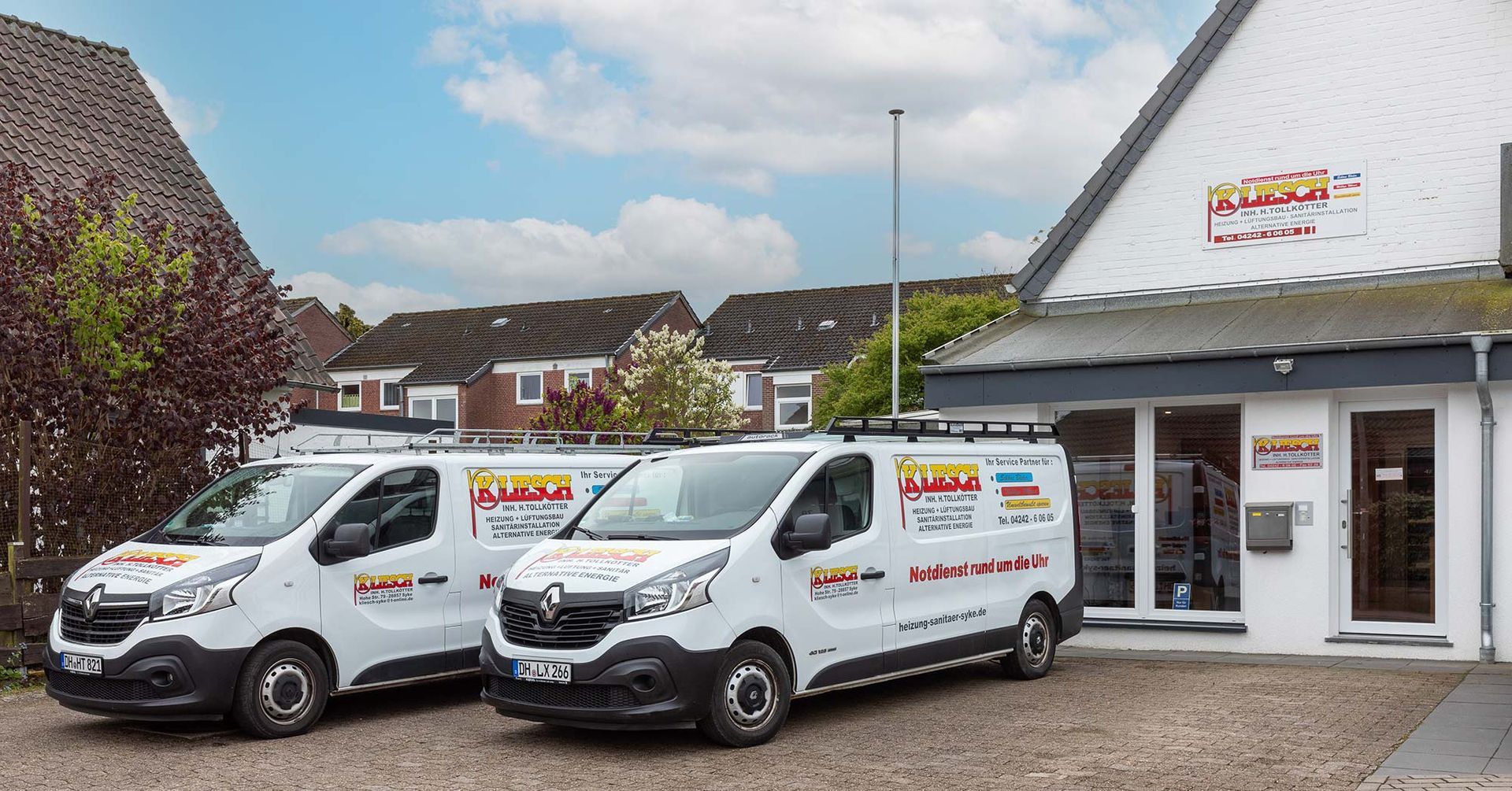 Zwei weiße Lieferwagen parken vor einem Gebäude.