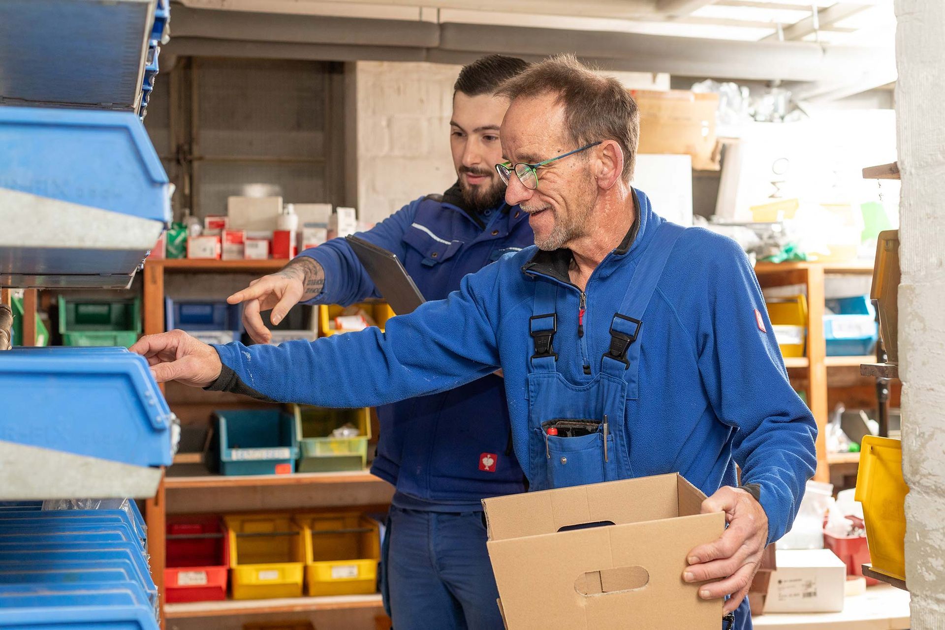 Zwei Männer arbeiten in einem Lager und einer hält eine Kiste.