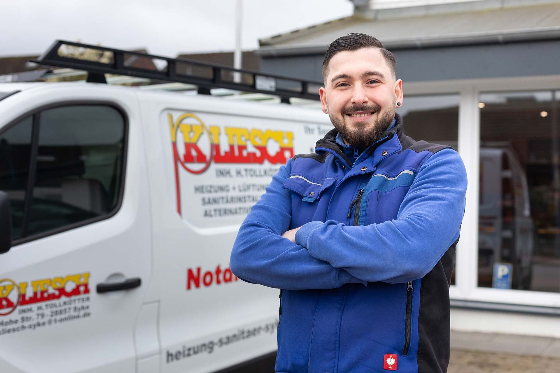 Ein Mann steht mit verschränkten Armen vor einem Lieferwagen.