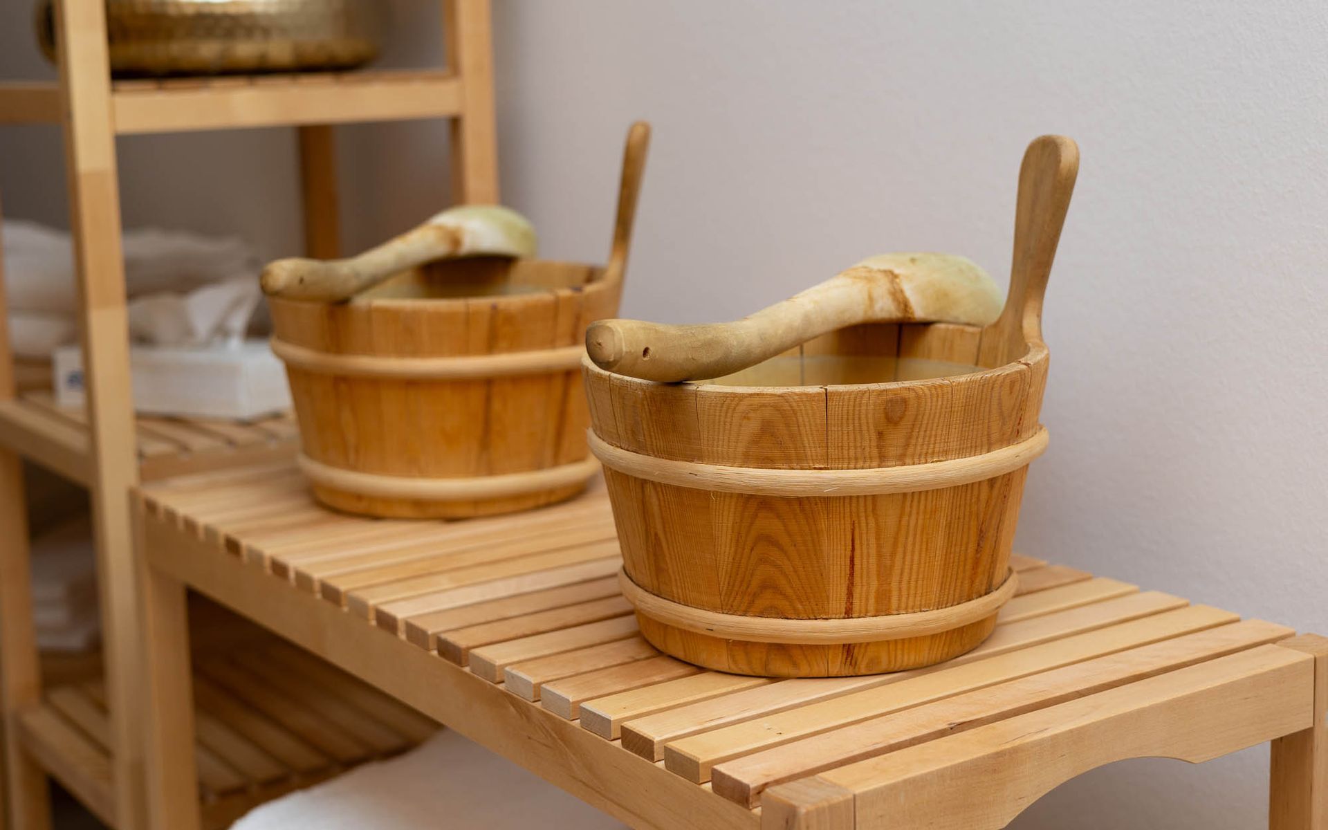 Zwei Holzeimer mit Holzlöffeln stehen auf einem Holzregal.