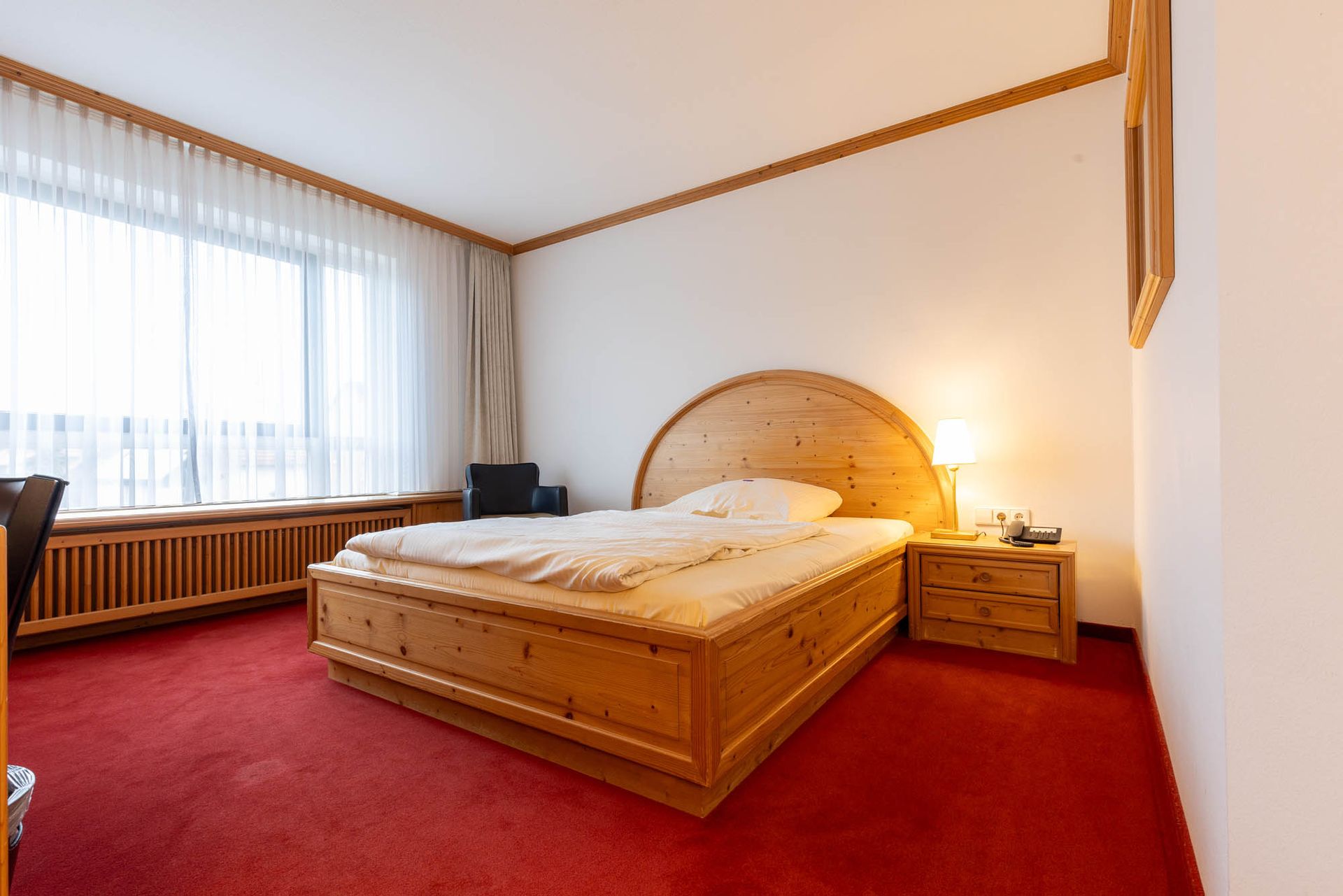Ein Hotelzimmer mit einem Holzbett und einem roten Teppich.