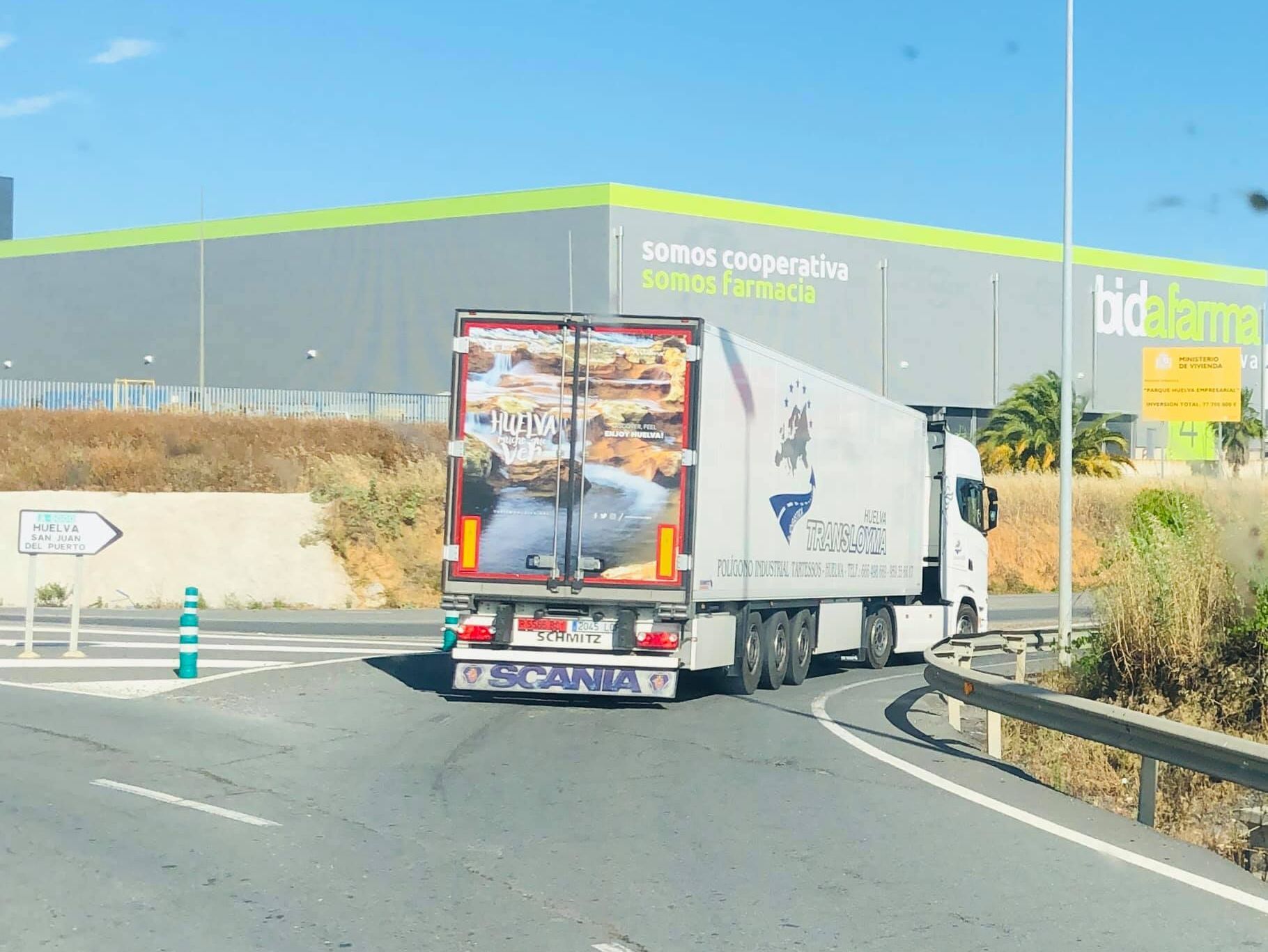 Un camión circula por una autopista frente a un edificio que dice bidalarme