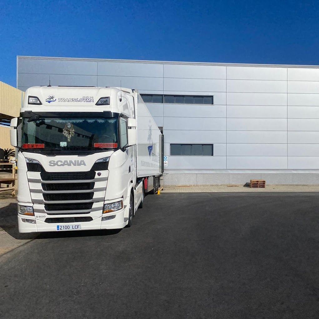 Un camión Scania blanco está estacionado frente a un edificio.