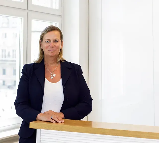 Eine Frau in einer blauen Jacke lehnt an einer Theke