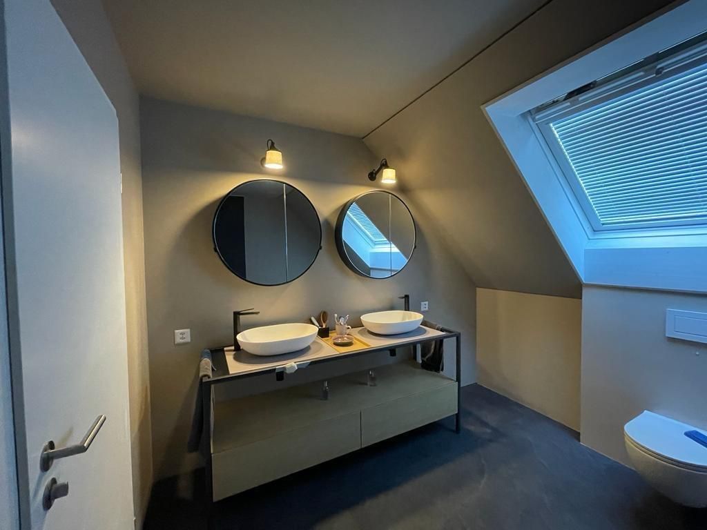 Ein Badezimmer mit zwei Waschbecken, zwei Spiegeln und einer Toilette.