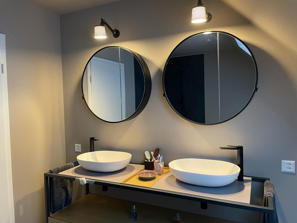 Ein Badezimmer mit zwei Waschbecken und zwei runden Spiegeln