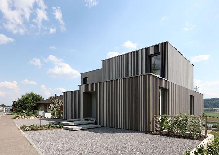 Ein modernes Haus mit einer Kiesauffahrt davor.