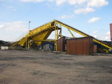 Una gran cinta transportadora amarilla está parada en un estacionamiento.