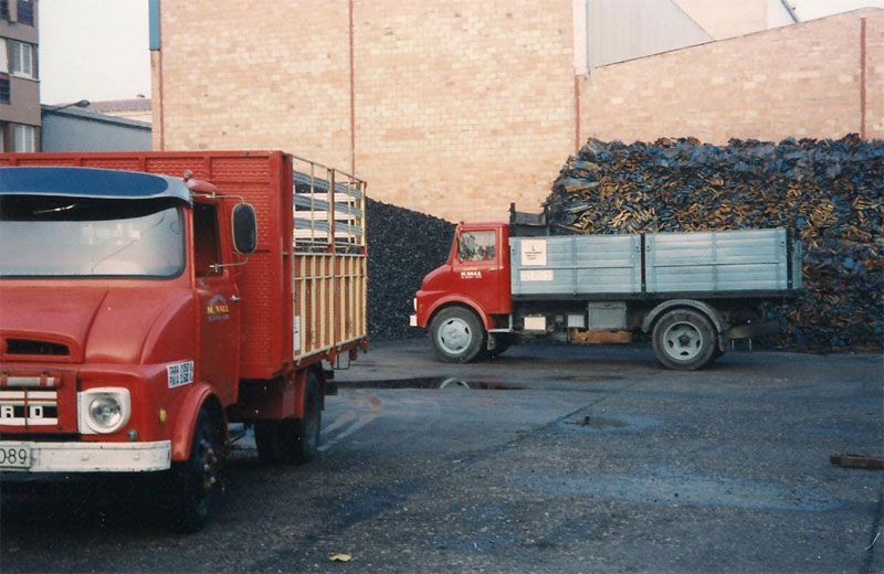 Dos camiones están estacionados frente a una pila de basura.