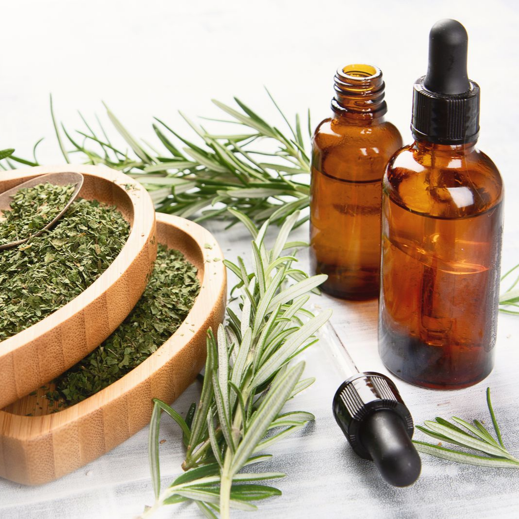 Des bols d'herbes médicinales, des brins de romarin et des flacons compte-gouttes.